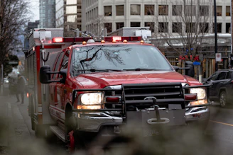 a red fire truck driving down a street next to tall buildings