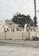 Raindrops are scattered across a window, with the blurred background showing a building and a message on a wall reading 'LA IS NOT SAFE'.