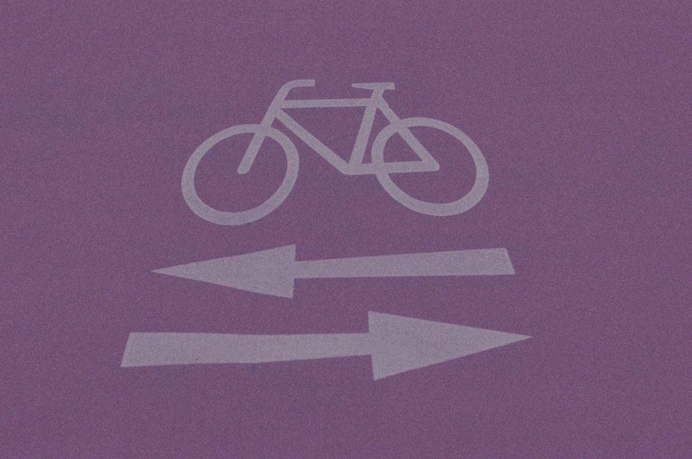 a purple sign with a bicycle and two arrows pointing in opposite directions