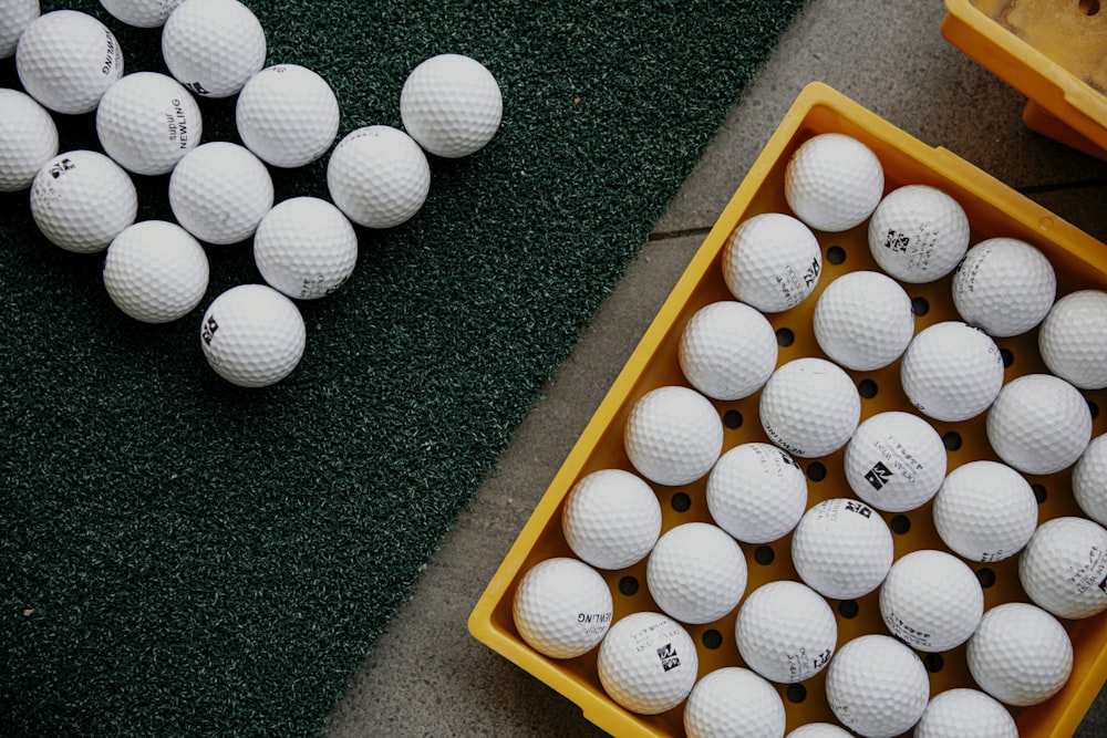 a bunch of white golf balls in a yellow box