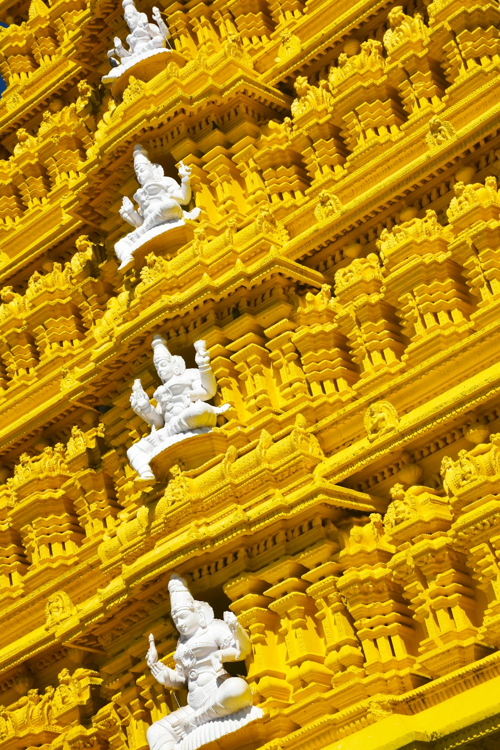 a yellow and white building with statues on it