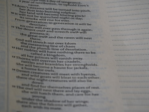 The image displays a close-up view of a page containing text, possibly from a religious or literary book. The text is arranged in verses and includes words like 'Edom's streams', 'desert owl', and 'thorns'. The text appears to have a poetic structure, with lines aligned and some parts featuring indented formatting.