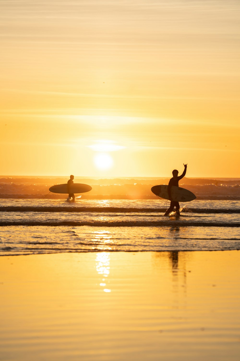 a couple of people that are standing in the water with surfboards