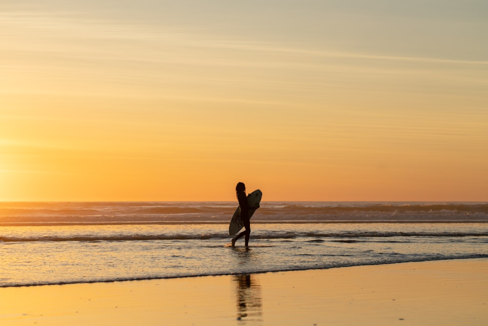 a person holding a surfboard walking on the beach