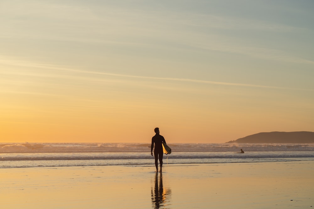 a person holding a surfboard walking on a beach