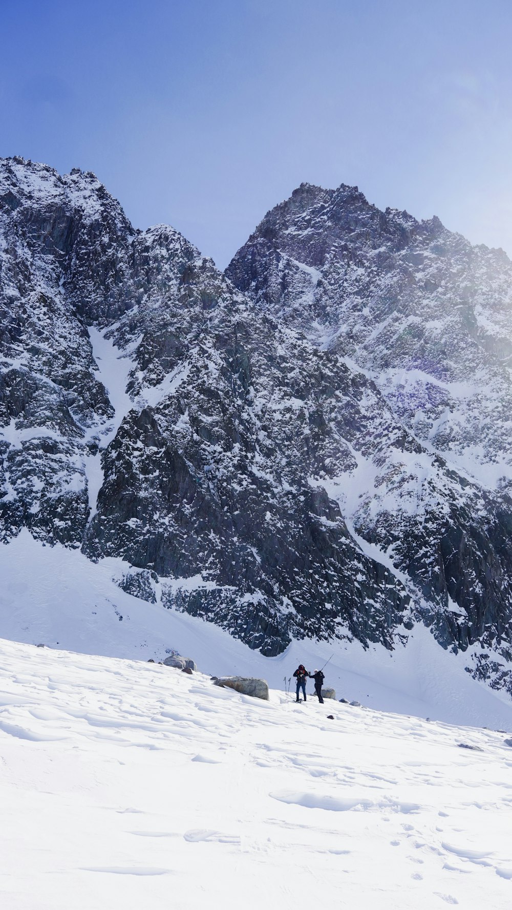 a couple of people standing on top of a snow covered slope