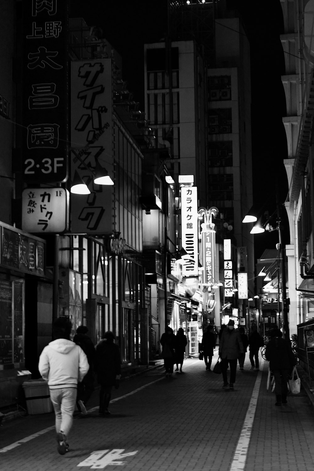 a group of people walking down a street next to tall buildings