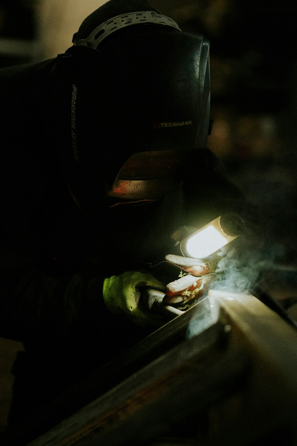 a man in a gas mask welding a piece of metal