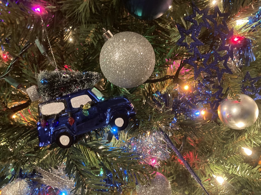 a christmas tree with ornaments and a toy car