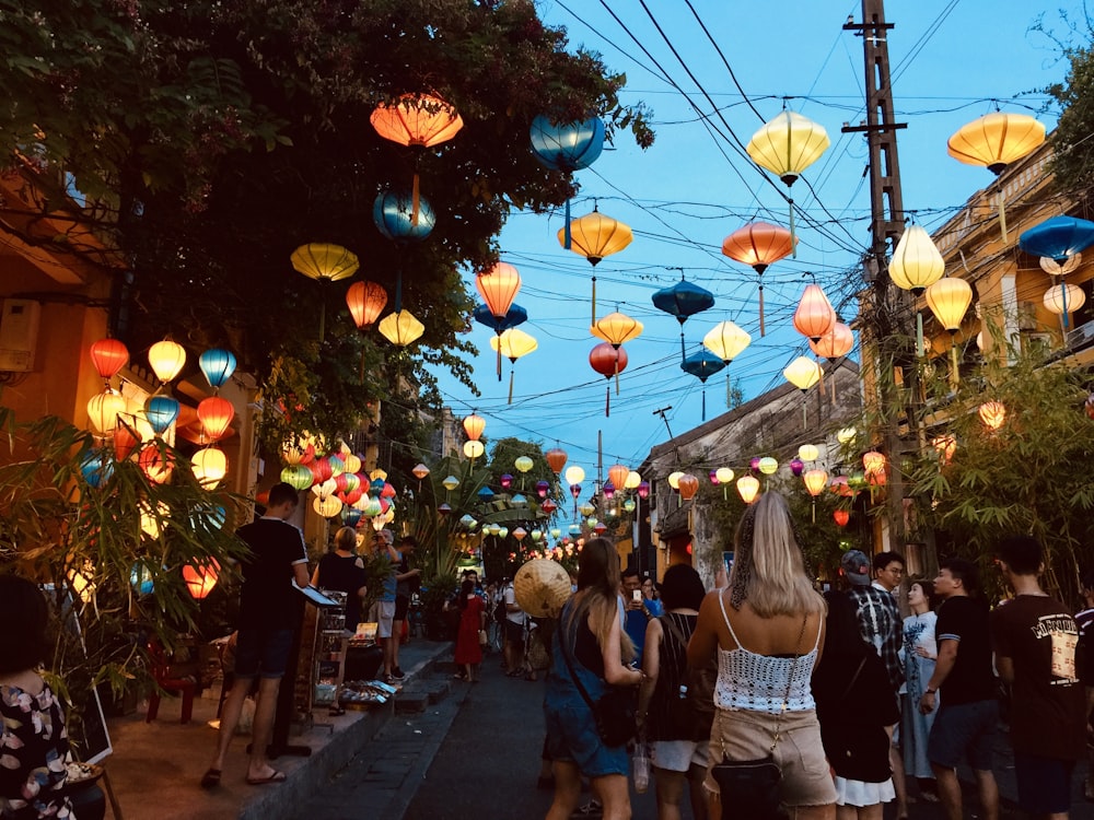 a group of people walking down a street under paper lanterns