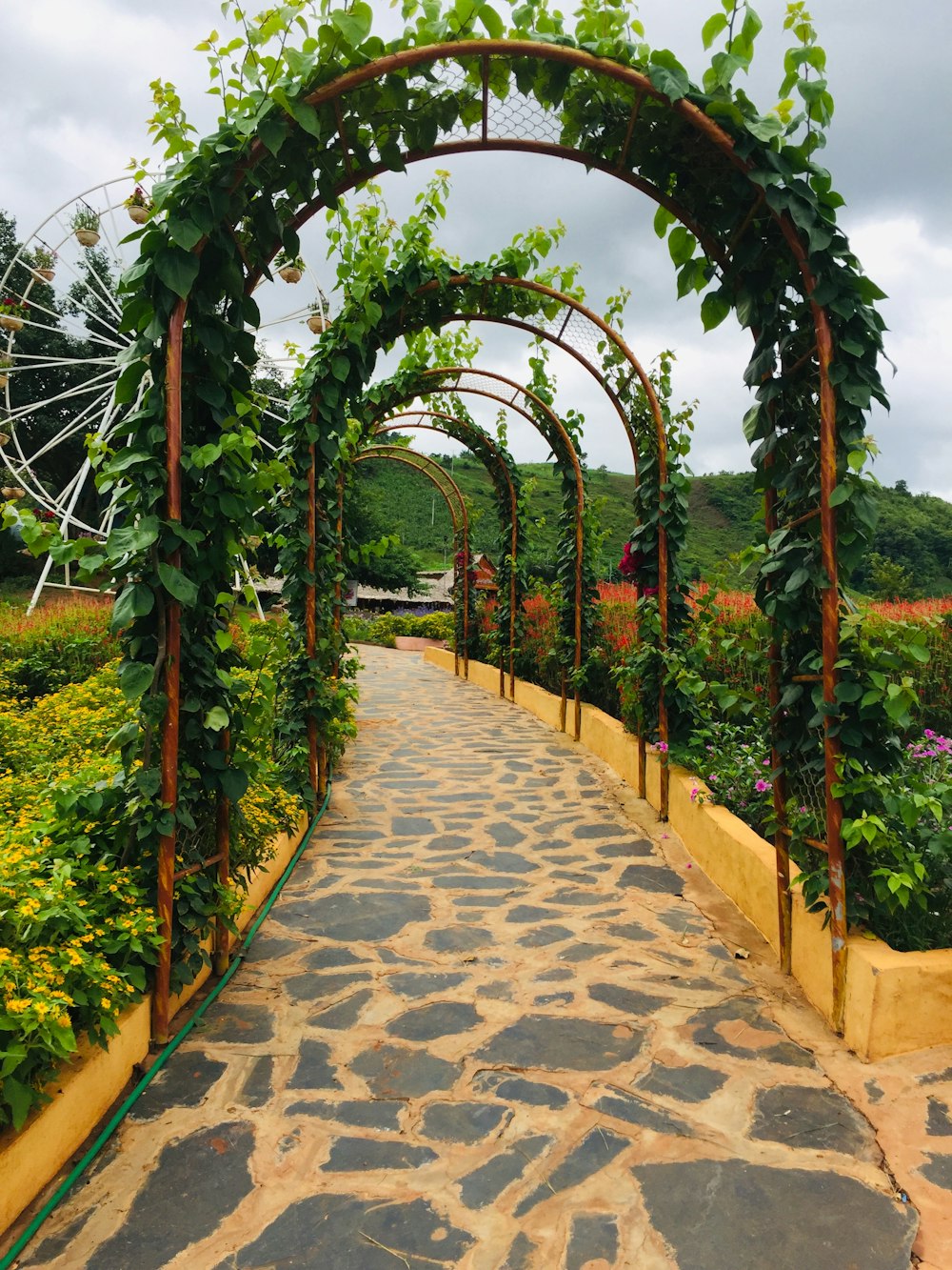 a stone path with a stone walkway between it and a ferris wheel in the background