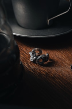 Close-up of the sleek mf ring resting on a wooden desk beside a laptop and a coffee cup.