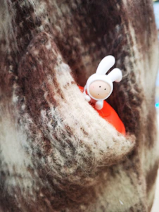 A close-up of a soft cotton tee featuring a playful rabbit graphic wearing a hard hat, set against a rustic wooden background.