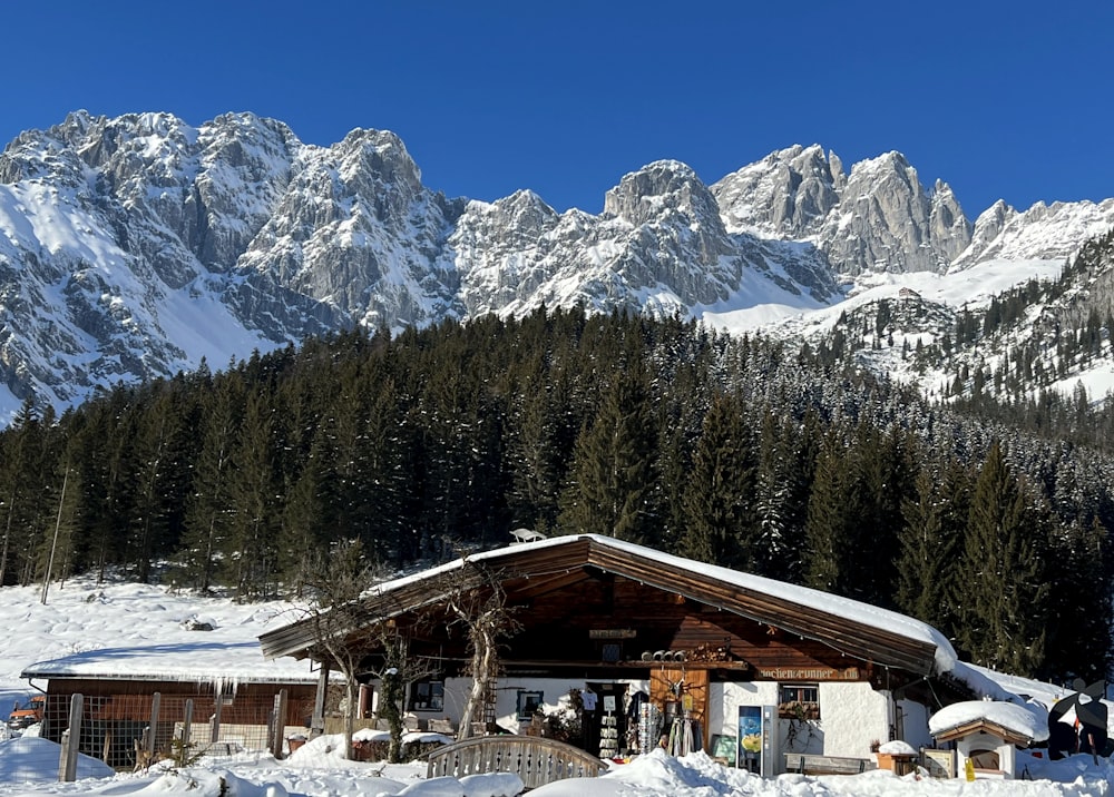 a cabin in the snow with mountains in the background