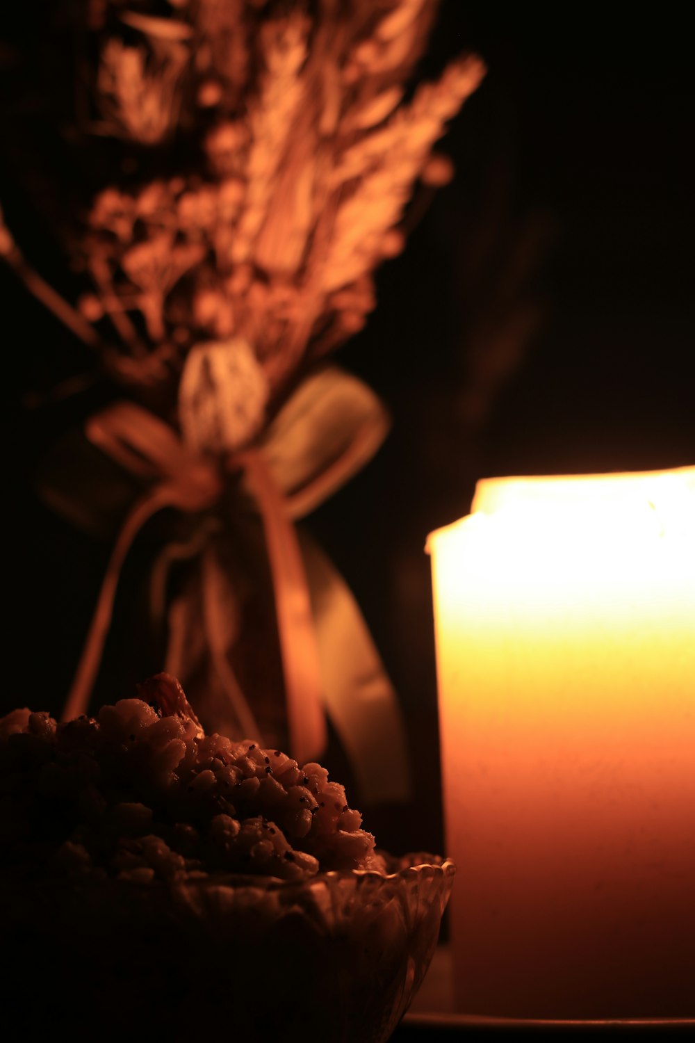 a lit candle next to a bowl of cereal