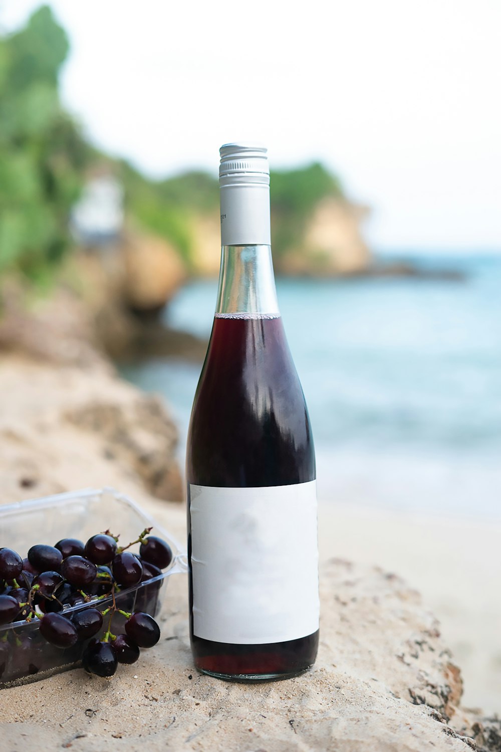 a bottle of wine sitting next to a container of grapes