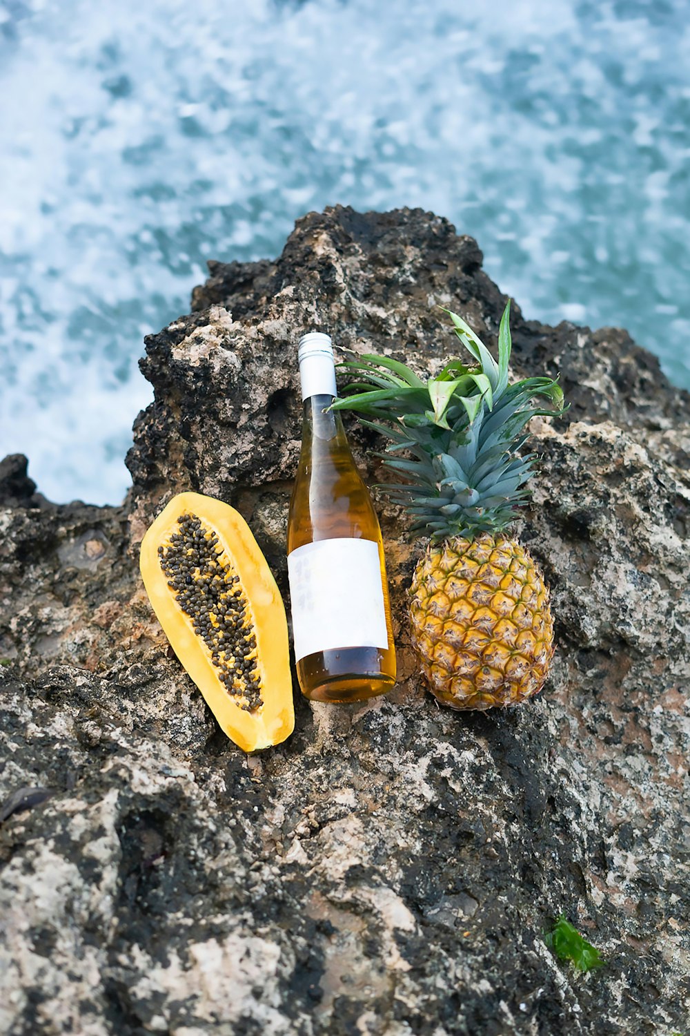 a pineapple and a bottle of wine on a rock
