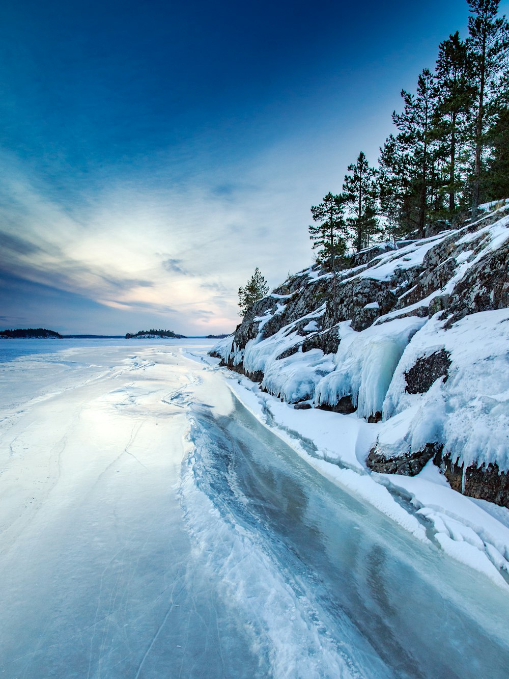 a frozen body of water next to a rocky cliff