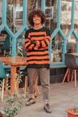 Smiling customer wearing a bold print sweatshirt while enjoying a city street café.