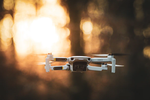 A dynamic FPV drone weaving through a dense forest at sunset, with electric blue light trails.