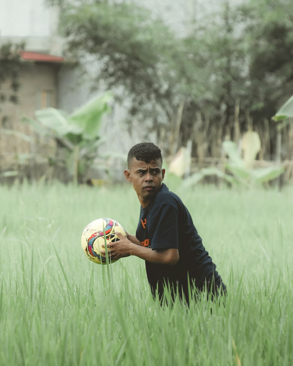 a man kneeling in a field holding a soccer ball