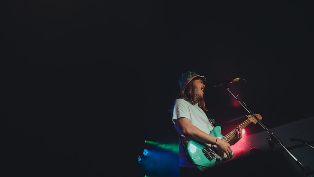 a man playing a guitar in front of a microphone