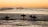 A group of surfers laughing and preparing their boards near the shore.
