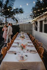 Romantic outdoor dining setup by the pool under string lights.