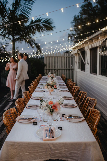 Elegant outdoor catering setup with linen-draped tables and twinkling fairy lights