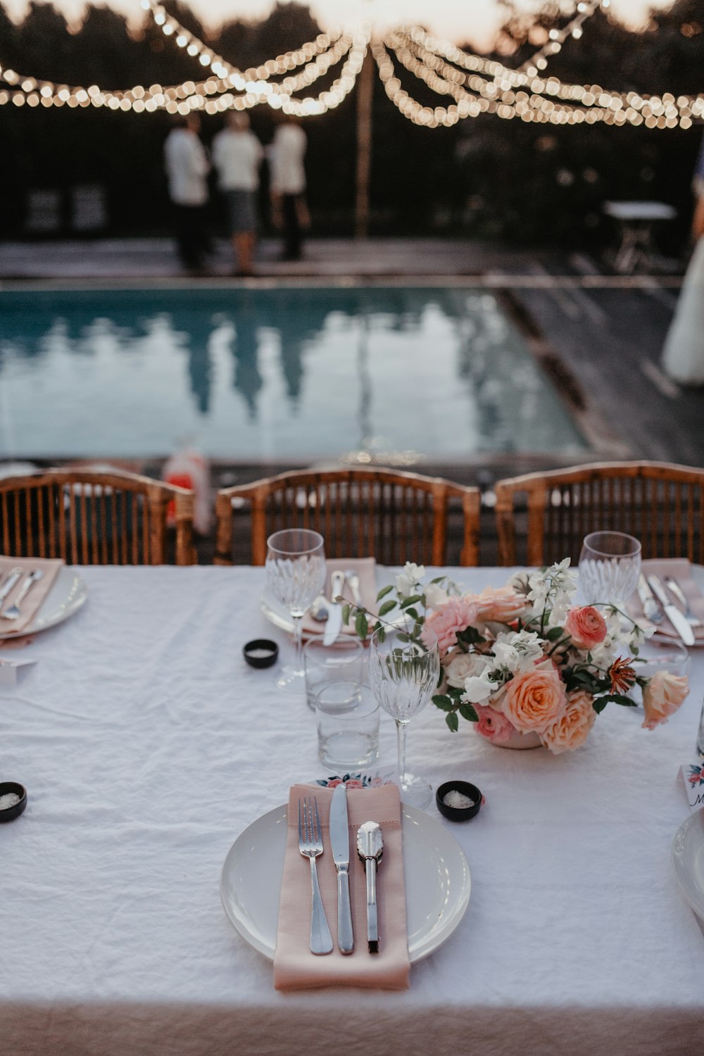 a table set for a wedding with a pool in the background