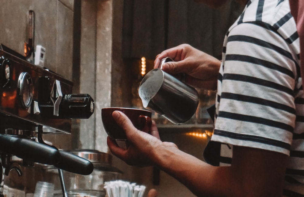 a person pouring a cup of coffee into a cup