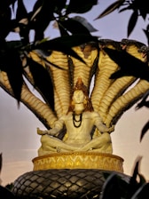 a statue of a woman sitting on top of a tree