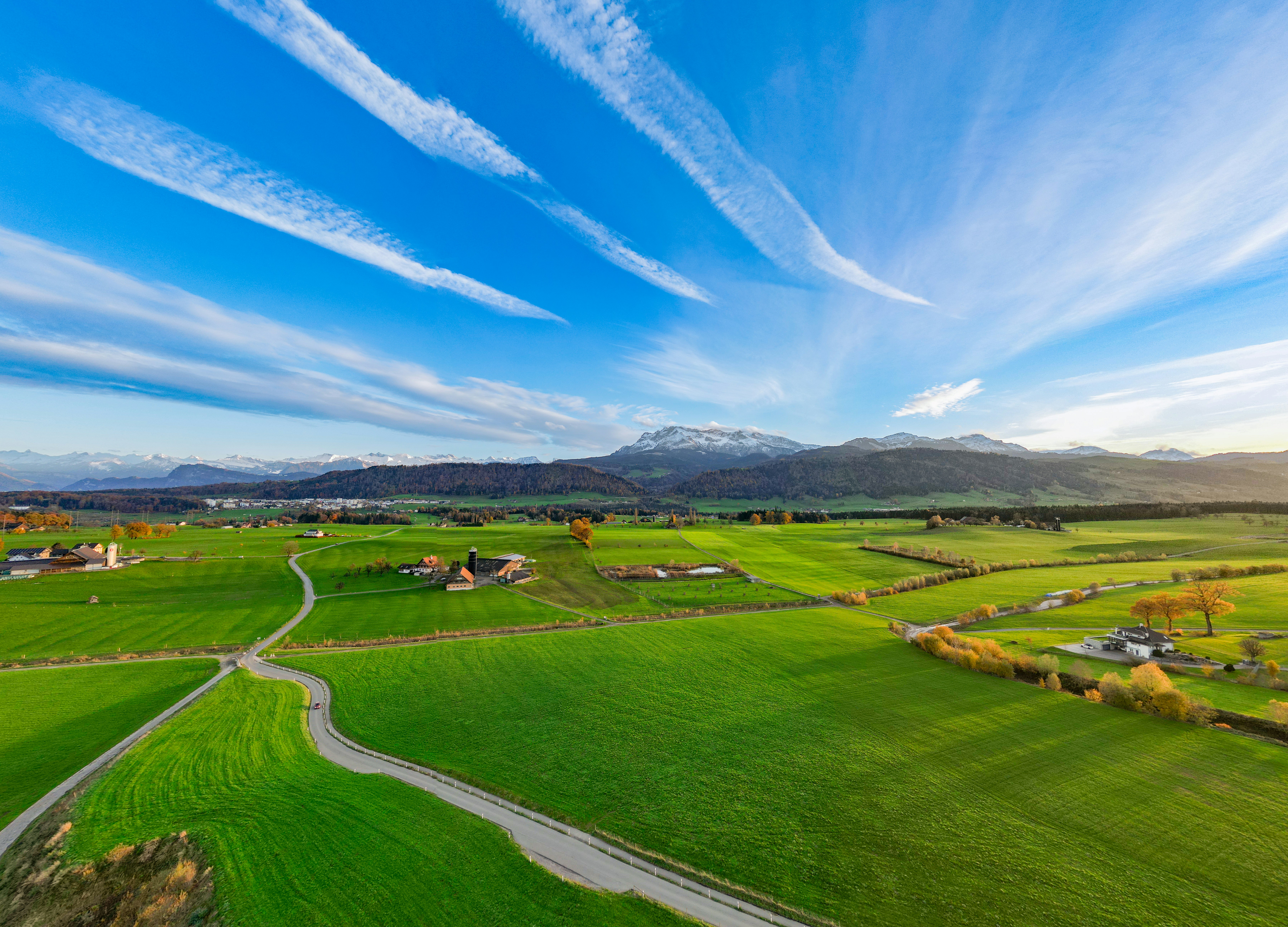 an aerial view of a green field with a road running through it