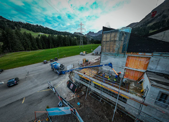 A scenic rural construction site with heavy machinery working amidst green fields and blue skies.