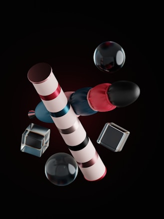 The image features geometrically arranged objects including striped cylindrical shapes, spheres, and transparent cubes. The objects are presented against a dark background and exhibit reflections and highlights, suggesting a glossy or metallic texture.