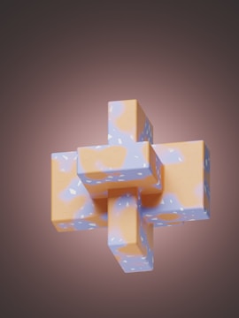 An abstract 3D shape composed of interlocking rectangular prisms with a smooth, glossy surface. The shape features a pattern of pastel colors including orange and blue, set against a dark, gradient background that gives a soft, glowing effect.