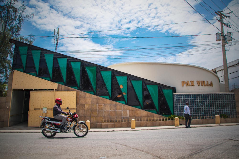 a man riding a motorcycle down a street next to a tall building