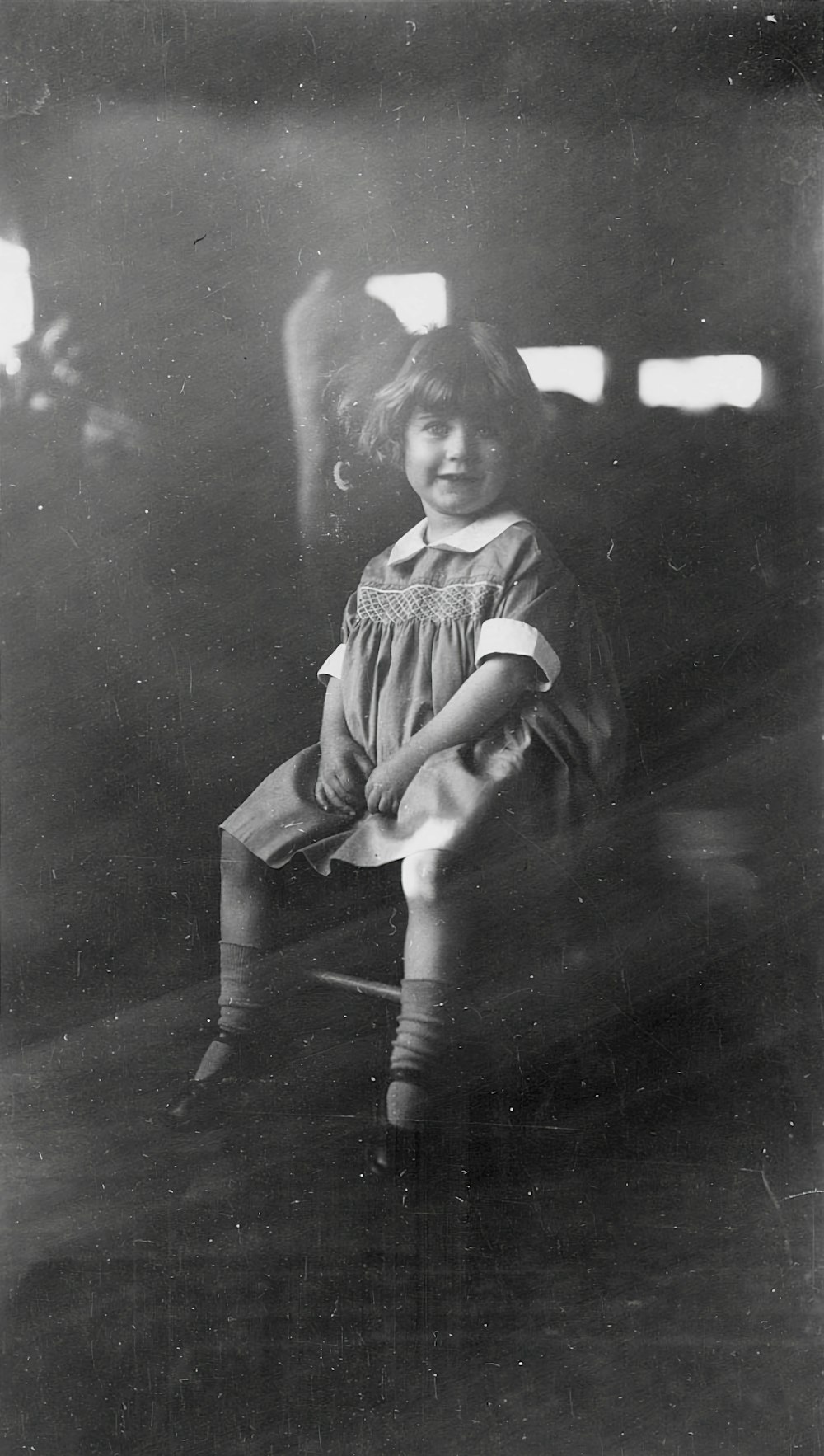 an old photo of a little girl sitting in a chair