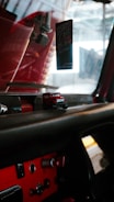 The image depicts the interior of a vehicle, focusing on the dashboard area. There is a small toy truck on the dashboard, and an air freshener hanging from the rearview mirror with a design that includes the words 'RokenrSoll'. The dashboard is mainly black with some red accents and has various buttons and controls.