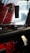 The image depicts the interior of a vehicle, focusing on the dashboard area. There is a small toy truck on the dashboard, and an air freshener hanging from the rearview mirror with a design that includes the words 'RokenrSoll'. The dashboard is mainly black with some red accents and has various buttons and controls.