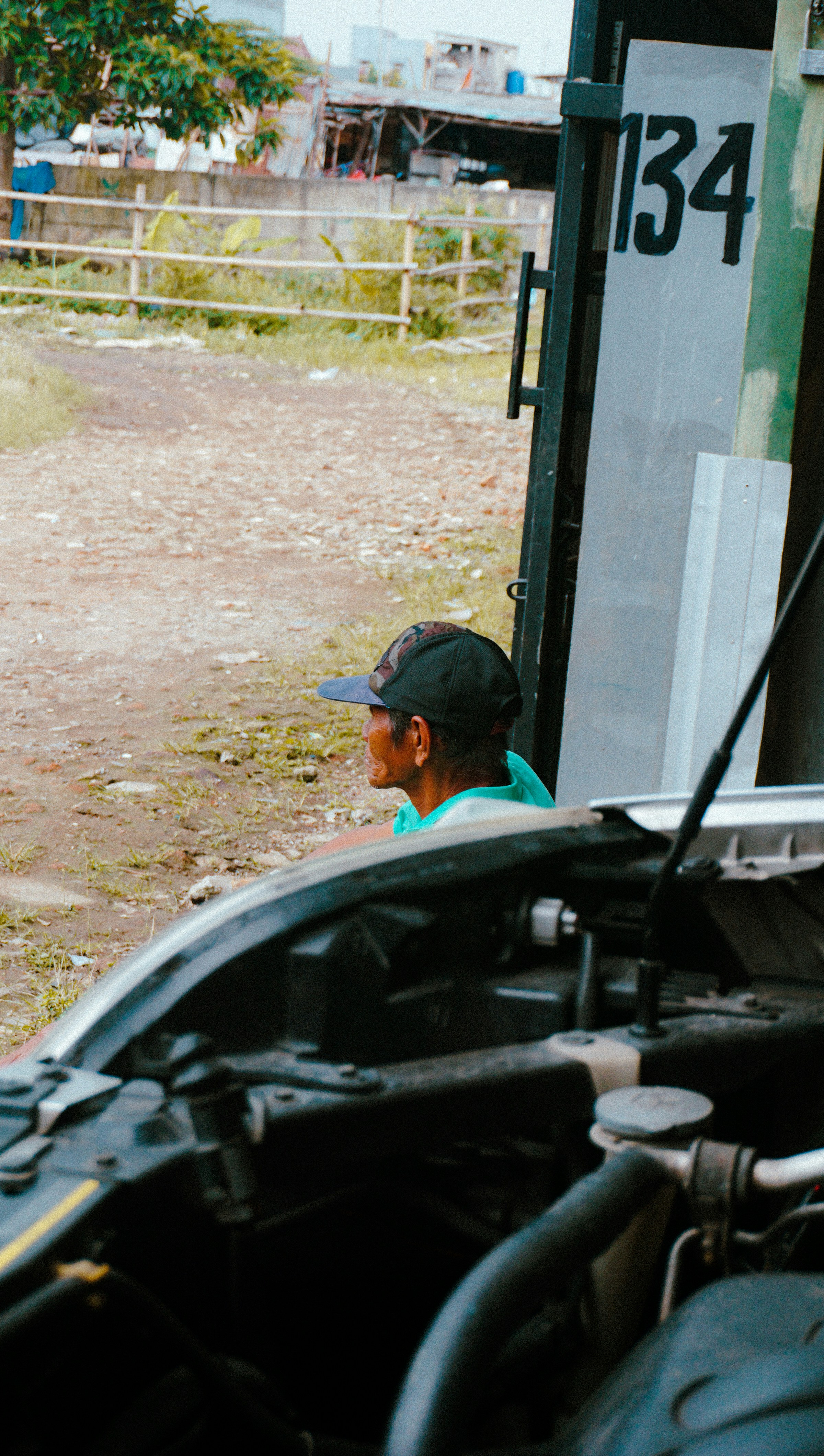 Seorang pria berdiri di samping truk dengan kap mesin terbuka