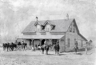 A sepia-toned photograph of early Wood County settlers gathered outside a rustic wooden cabin.
