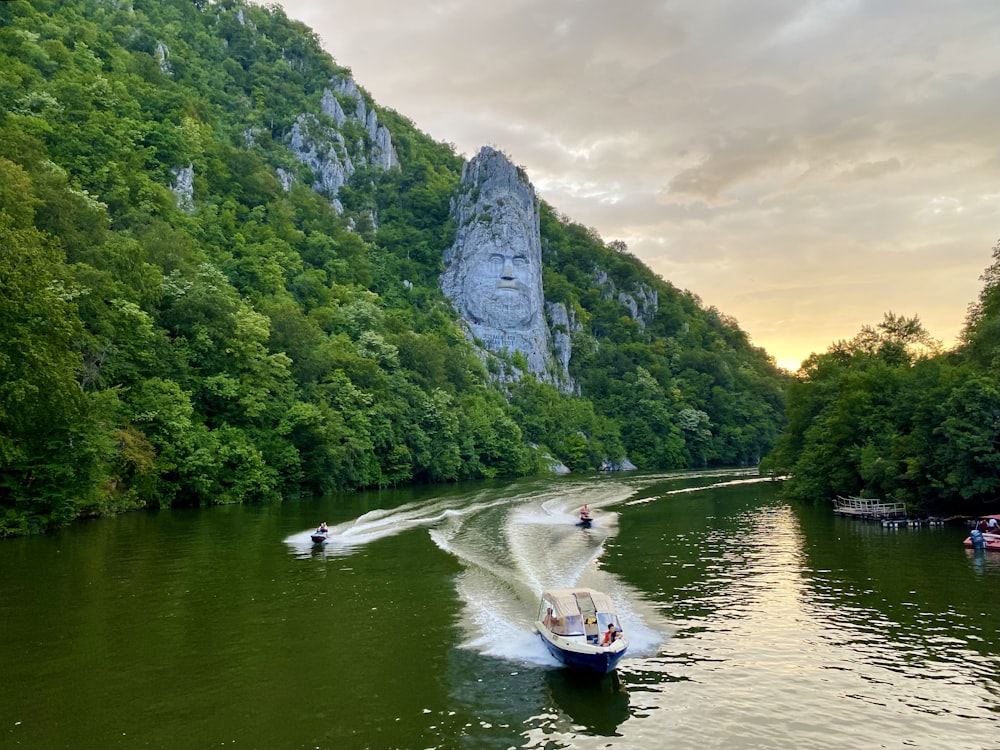 a boat traveling down a river next to a mountain