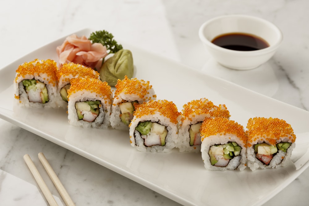 a white plate topped with sushi next to a cup of coffee