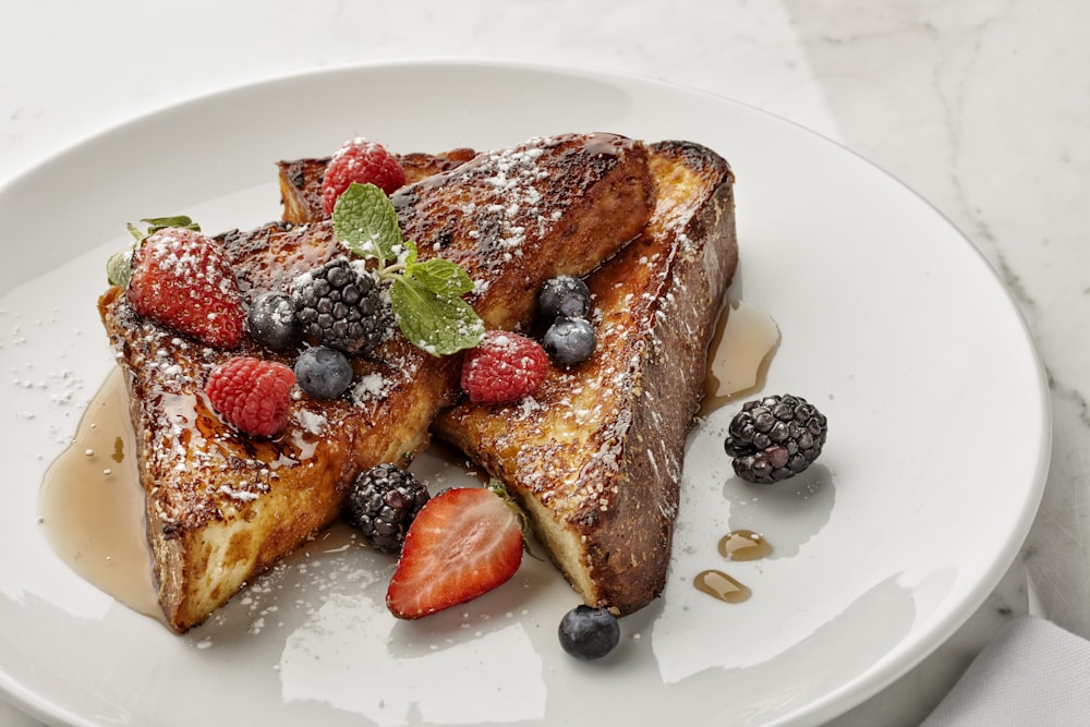 a white plate topped with french toast and berries