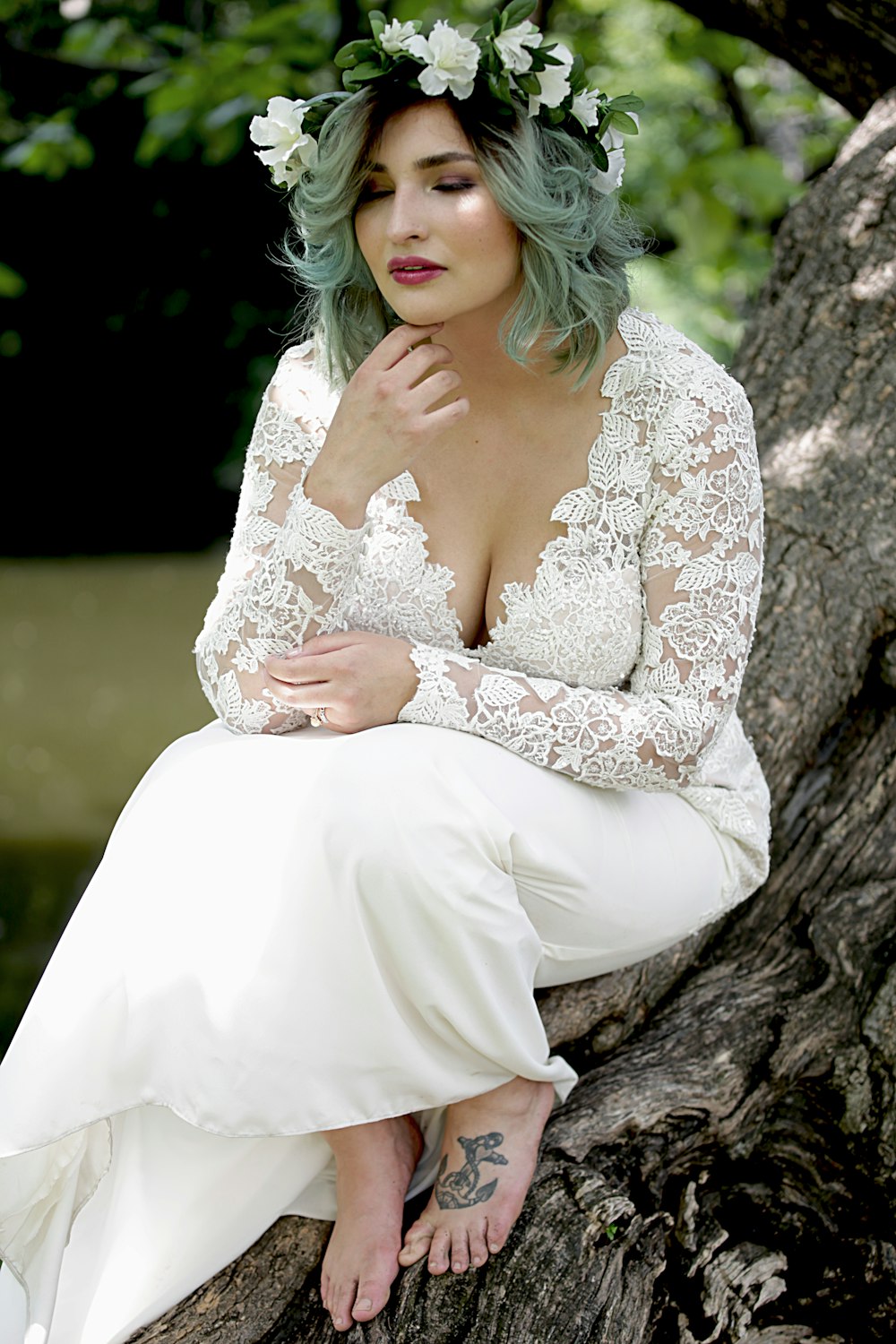 a woman with green hair sitting on a tree branch