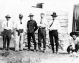A group photo with men smiling, standing in front of the ranch welcome sign.