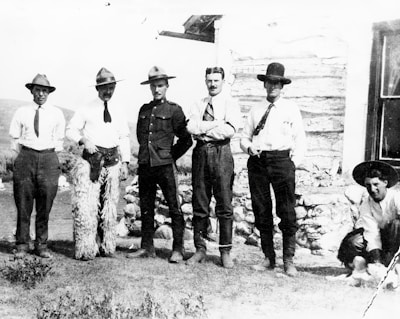 A group photo with men smiling, standing in front of the ranch welcome sign.