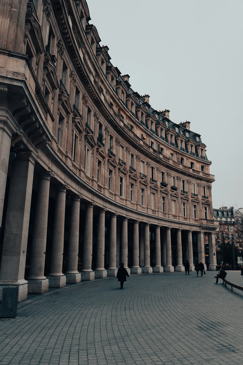 a large building with columns and people walking around it