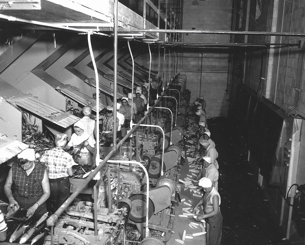 a black and white photo of men working in a factory